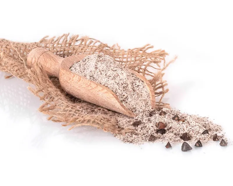 Farina integrale di grano saraceno in una sessola di legno, sulla juta, coi chicchi sparsi