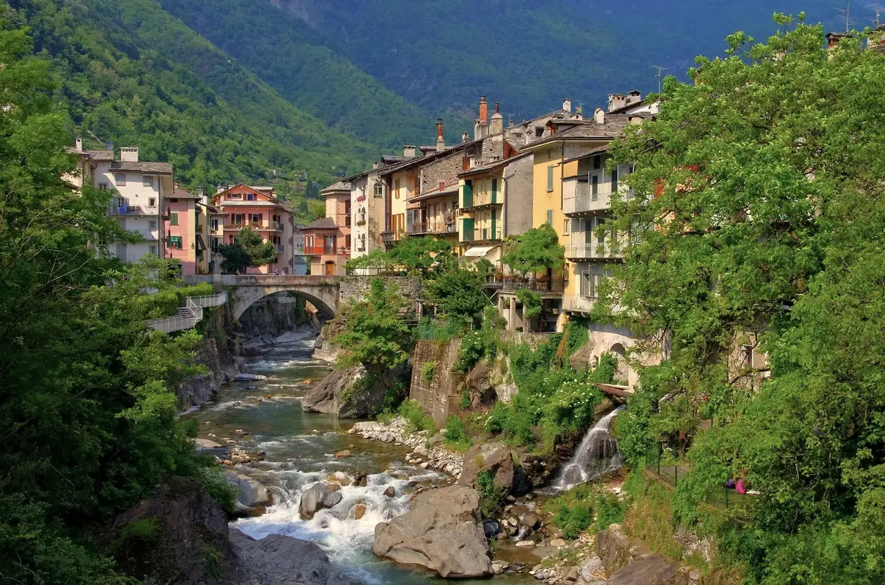 Chiavenna: le case sul fiume Mera, il ponte di pietra, l’acqua che scende fra le rocce e una cascatella