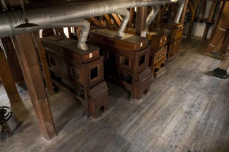 Il legno scuro delle macchine del mulino visto dall’alto, fra le travi