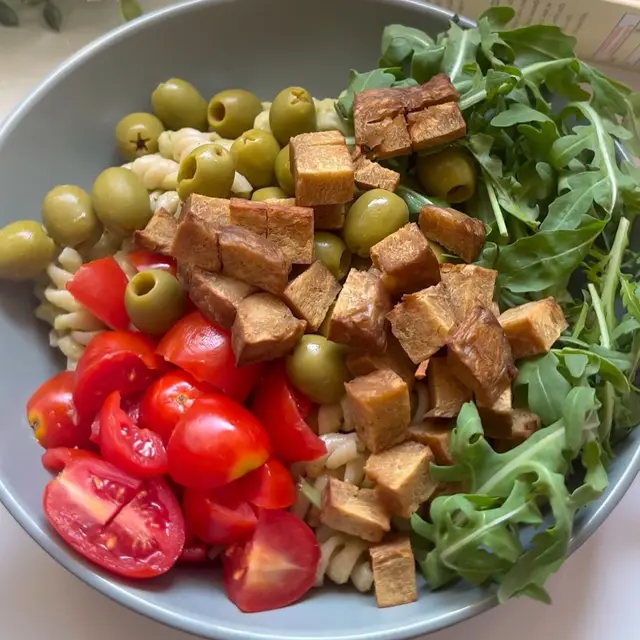 Una ciotola di fusilli con segale con seitan, pomodorini, olive e rucola