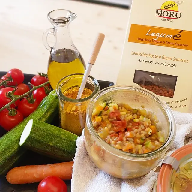 Legumé con le verdurine in un vasetto di vetro, coi pomodori, le zucchine e la confezione arancio